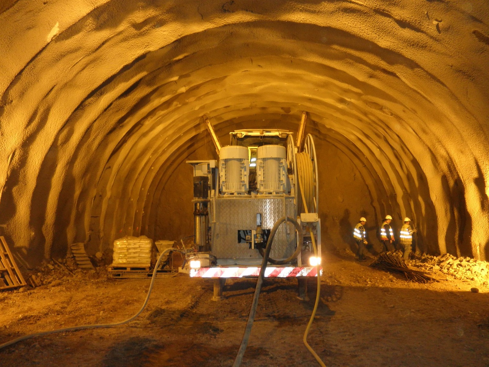 Shotcreted horseshoe tunnel profile with grouting plant and workers